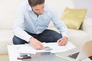 Young man reviewing bills. If you find yourself in debt, it is important to understand if and when a creditor can freeze your bank accounts.