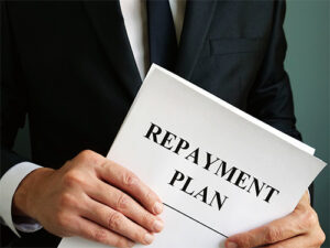 Man holing paper with the words "Repayment Plan" printed on it.