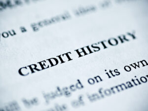 The phrase "CREDIT HISTORY" on a piece of paper with surrounding text.