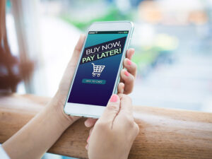 Woman holding a smartphone with "Buy now, pay later" displayed on the screen.
